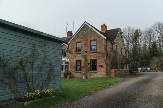 Home Exterior in United Kingdom. Old farmhouse exterior image. Located in England in the Somerset countryside. Contemporary doors and windows in traditional farm house building.