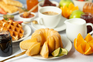 Table with various muffins, muffins, fruits and coffee cups on a light background.