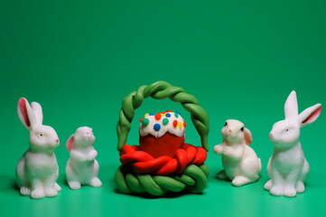 Figures of toy rabbits and Easter cake on a green background.