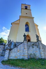 Tall church tower with baroque statues on the stone wall