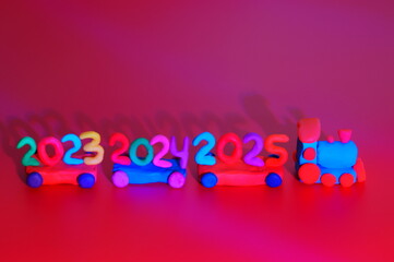 A toy train made of plasticine with the numbers 2023, 2024, 2025. A festive event. Christmas and New Year. Calendar date.