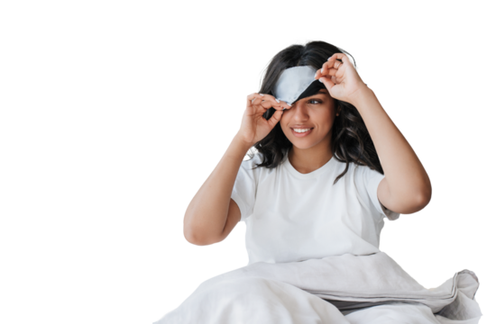 Young African American girl with wavy hair sitting on bed under blanket takes off sleeping mask looks away toothy smiles against transparent background, Cheerful young Brazilian woman, morning, hotel.
