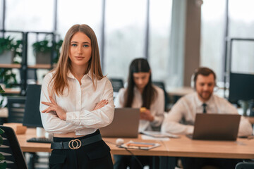 Woman is standing in front of her colleagues. Business people in formal clothes are working in the office together