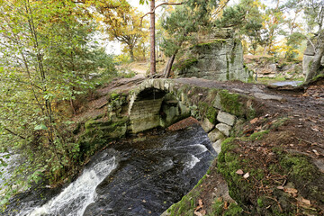 Old medieval stone bridge over the forest stream