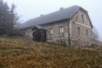 Old house with wooden porch in the autumn fog