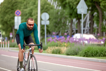 A cyclist man rides a bike in a city park along a bike path.