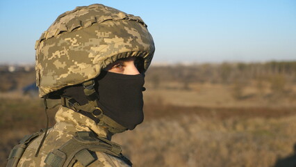 Gaze of male ukrainian army soldier in helmet and balaclava outdoor. Profile view of young military man looking with hope of victory. Invasion resistance. War between russia and Ukraine. Close up