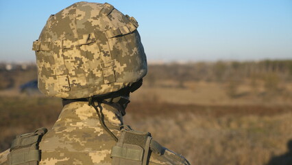 Gaze of male ukrainian army soldier in helmet and balaclava outdoor. Profile view of young military man looking with hope of victory. Invasion resistance. War between russia and Ukraine. Close up