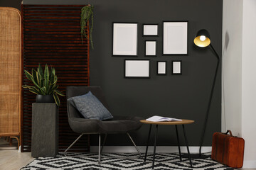 Empty frames hanging on black wall in stylish room. Mockup for design