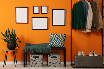 Empty frames hanging on orange wall in stylish room. Mockup for design