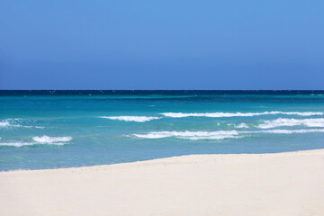 Empty sea beach with white sand, view to azure waves and blue sky. Caribbean coast, Background for holidays on a paradise nature