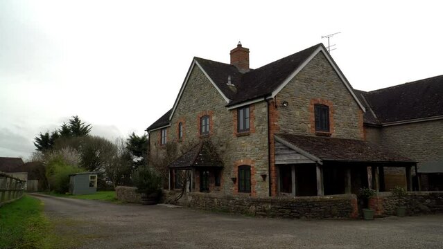 Home Exterior in United Kingdom. Old farmhouse exterior image. Located in England in the Somerset countryside. Contemporary doors and windows in traditional farm house building.