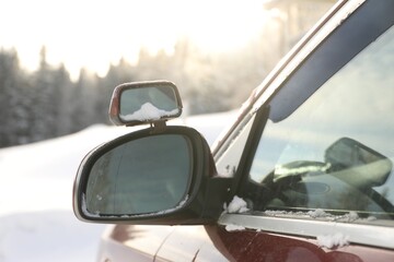 Side view mirror of car on snowy winter day, closeup