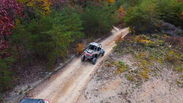 Aerial shot of UTVs driving down a hill while trail riding during autumn.