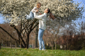 Naklejka na ściany i meble Young mother and her cute daughter having a fun in spring time park in Prague, Europe