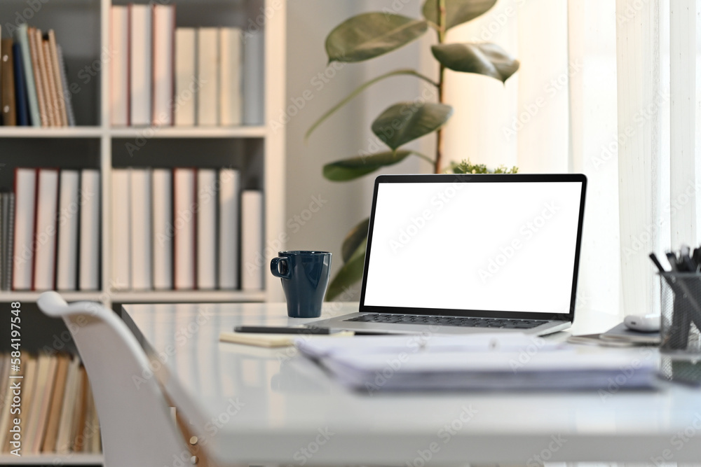 Wall mural White working desk in modern home office with laptop computer, coffee cup and documents. Blank screen for advertising design