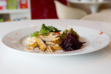 Healthy spicy chicken on a white plate with shredded beetroot & cuscus.