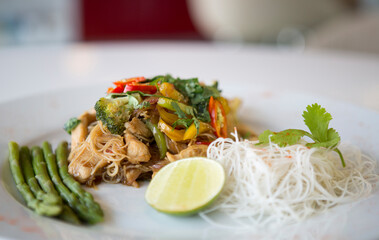 Chicken with noodles & green vegetables, red chillis & coriander, in a restaurant.