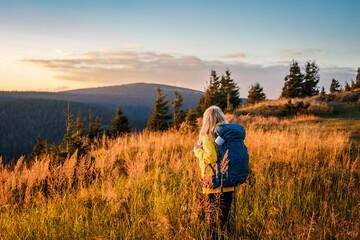 Fototapeta na wymiar Woman with backpack looking at mountain range in natural parkland Jeseniky during sunset. Landscape with hiking tourist