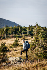 Fototapeta premium Woman hiking in mountains. Tourist with backpack walks on trekking trail. Adventure in nature