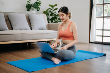 Obraz premium Asian Woman Doing Yoga and Watching Online Tutorials on Laptop, Training in Living Room