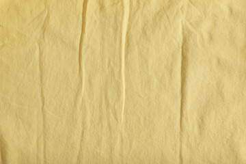 Crumpled pale yellow fabric as background, top view