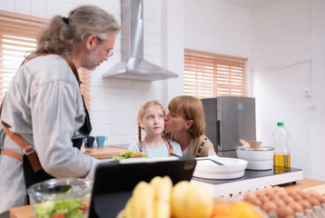 Grandparents with grandchildren and children gather in the kitchen to prepare the day's dinner.