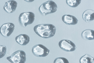 Drops of serum or hyaluronic acid gel with bubbles on a blue background. Smears of cosmetic skin care products. Wellness and beauty concept.