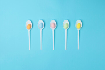 Flat lay colorful Easter Eggs on the spoon. Blue background. Horizontal format.