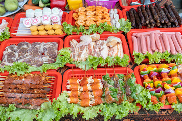 Fototapeta na wymiar Raw steaks, sausages, meat, and vegetables on skewers in Vietnamese street market