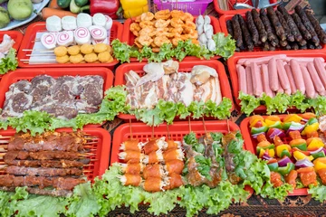 Fotobehang Raw steaks, sausages, meat, and vegetables on skewers in Vietnamese street market © vadiml
