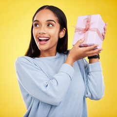 Happy woman, excited and gift box in a studio with a smile from surprise present for birthday. Giveaway prize, isolated and yellow background of a young female student feeling positive and cheerful