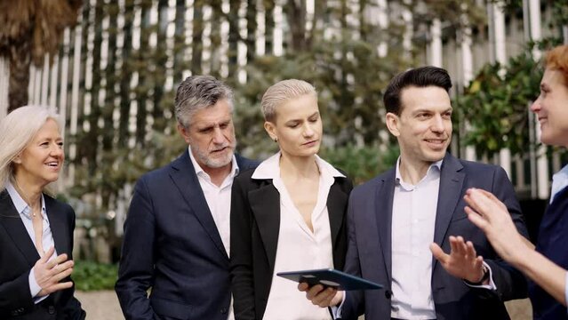 Business people using a tablet during a business meeting outdoors