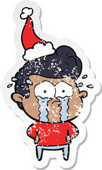 distressed sticker cartoon of a crying man wearing santa hat