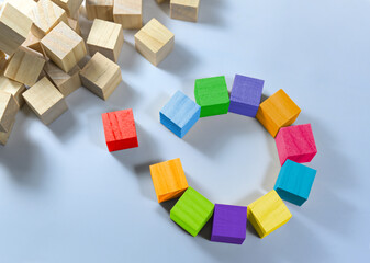 Cubes in different colors together form a circle with a gap, one is red and stands separate, heap...
