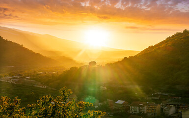 beautiful landscape,  golden sunset with amazing view from highland to a valley with town, nice mountains and scenic cloudy sunset on background