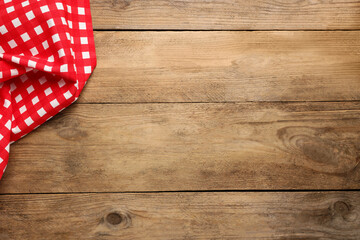 Checkered tablecloth on wooden table, top view. Space for text