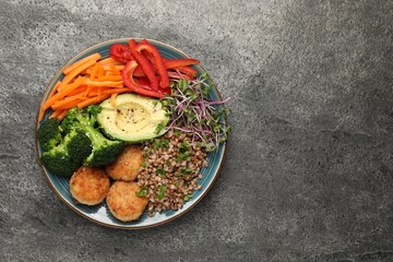 Delicious vegan bowl with cutlets, buckwheat and broccoli on grey table, top view. Space for text