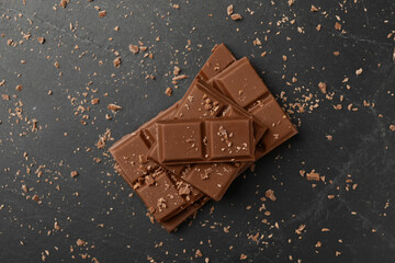Pieces of tasty chocolate on grey table, top view