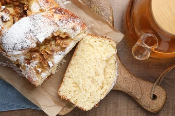Delicious yeast dough cake and cup of tea on wooden table, flat lay