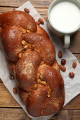 Delicious yeast dough cake, nuts and cup of milk on wooden table, flat lay