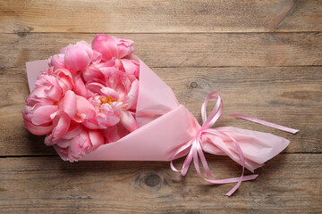 Beautiful bouquet of pink peonies on wooden table, top view
