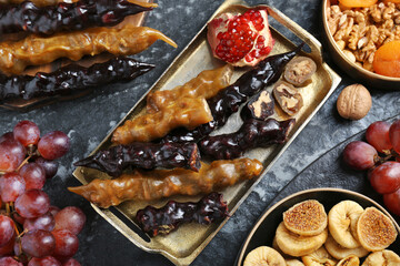 Delicious sweet churchkhelas and ingredients on textured table, flat lay