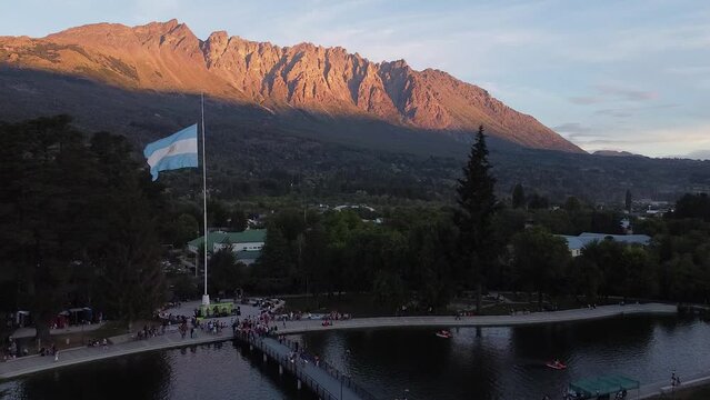 Argentinian flag waving over an artificial lake and a bridge. Patagonian mountains in the background. Drone aerial shot. El Bols&oacute;n.