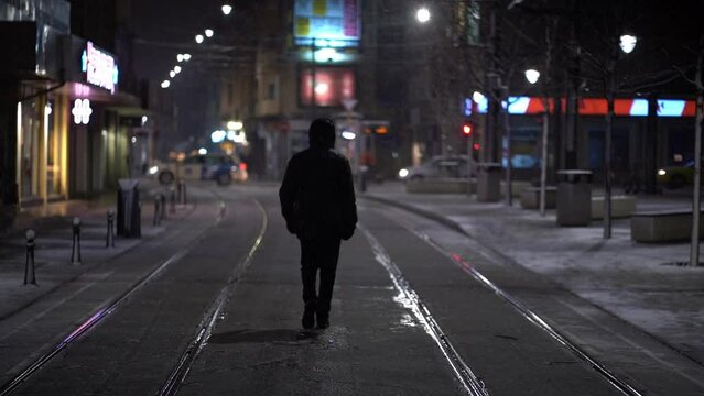 Person walks in middle of empty side street on cold snowy night