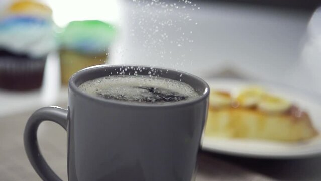 Sugar crystals falling into cup of coffee - slow motion