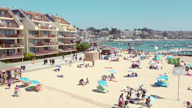Slow motion dolly shot above tourists sunbathing on the Pejerrey beach in Chile