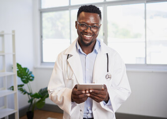 Portrait of a young Black doctor using digital tablet in bright office