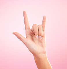 Hands, closeup and woman in studio with rock and roll sign, gesture or symbol against pink...
