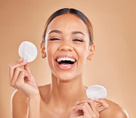 Face, funny and woman with cotton pad, skincare and happiness against a brown studio background. Portrait female and lady laughing, makeup remover and foundation with smile, dermatology and grooming